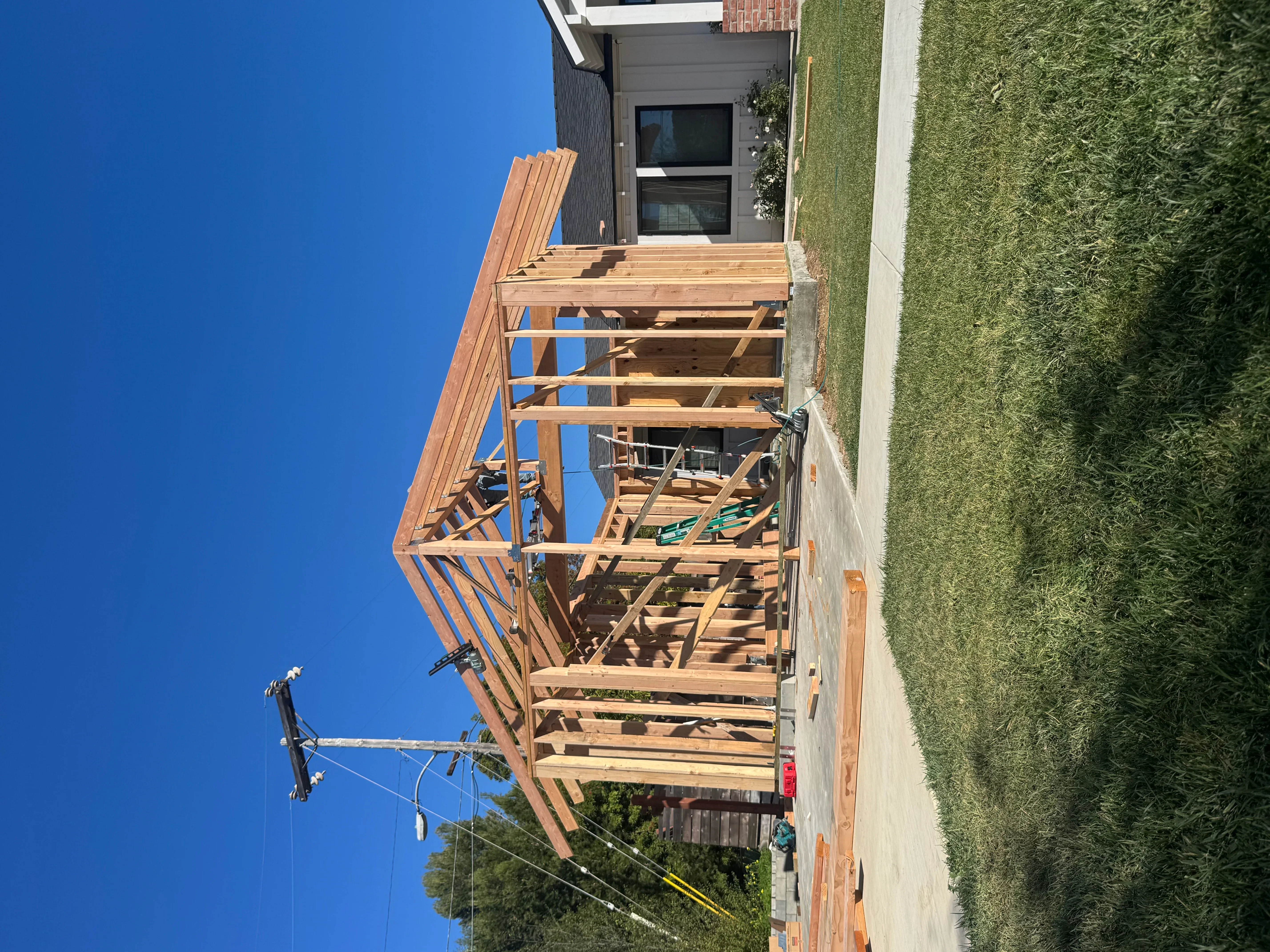 Pressure-treated wood deck framing with angled roof structure and support beams under construction