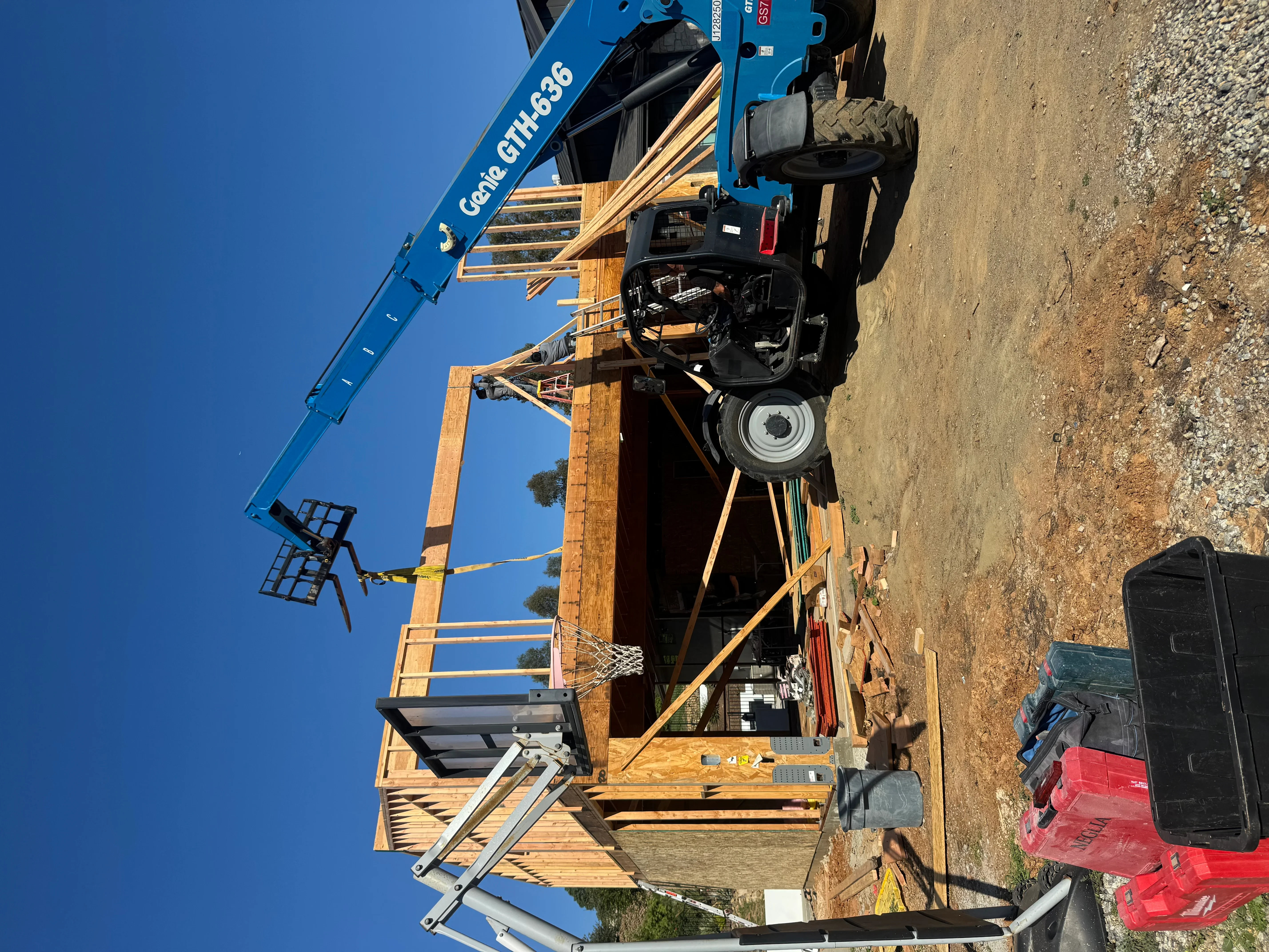 Wooden residential framing with structural posts, beams, and blue crane for material handling on construction site
